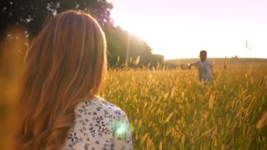 Mutlu Asyalı çocuk buğday alanın güneşli güzel doğada memnun annesi sarılmaya çalışır