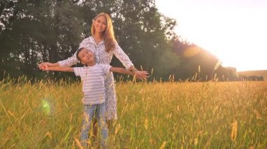 Sevimli küçük oğlu ve el ele tutarak ve günbatımı üzerinde sarı zemin üzerinde gülümseyen mutlu Asya Anne geri duruyor