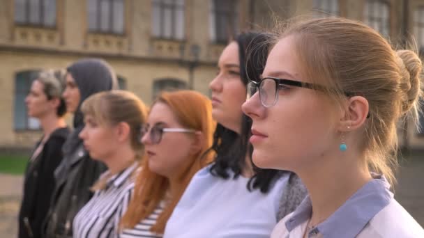 Diverso grupo de chicas caucásicas jóvenes de pie en el perfil exterior juntos mirando hacia otro lado — Vídeos de Stock