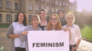 Çeşitli gurup işareti ile ayakta ve dışarıda gülümseyen Genç beyaz feministler