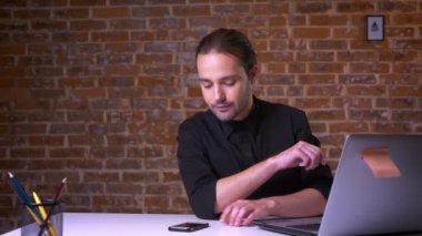 Beyaz işadamı gülümseyen çalışmaları durdu ve tuğla Studio kazanan hareketi ile smartphone vasıl baktı