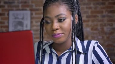 kendine güvenen genç Afrikalı kız onun laptop ve sonra kameraya bakarak ve kapalı gülümseyen üzerinde konsantre