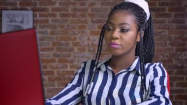 Mevduat Tasarruf Mevduatı bilgisayarda seyir consentration th tuğla Studio ile çalışma masasında otururken unjoyful Afrikalı kadın sakin