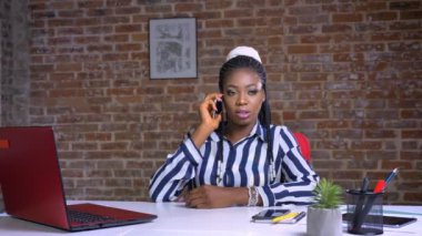 telefonla konuşurken ve kapalı onun işyerinde rahat bakışla gülümseyen şirin Afrikalı kız