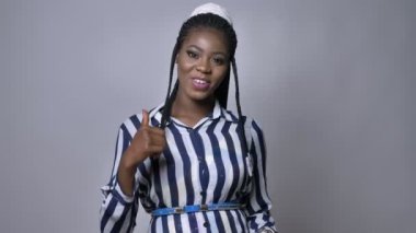 Tamam gösterilen mutlu Afrikalı gülümseyen kız kameraya ovet gri arka plan ayakta iken iç