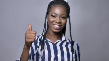 şirin mutlu Afrika kadın gösterme gibi jest ve gri duvarının yakınında duran güzel gülümseme ile kameraya bakıyor