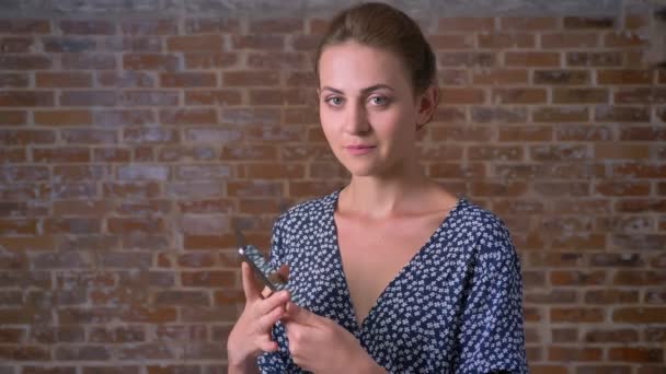 Jolie caucasienne jeune femme montre écran vert sur tablette et clin d'oeil heureux debout à côté du mur de briques — Video