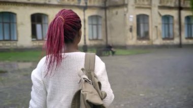 Genç Afrikalı kız öğrencinin Üniversite, sırt çantası ve pembe dreadlocks ile büyüleyici kadın olacak hareketli çekim
