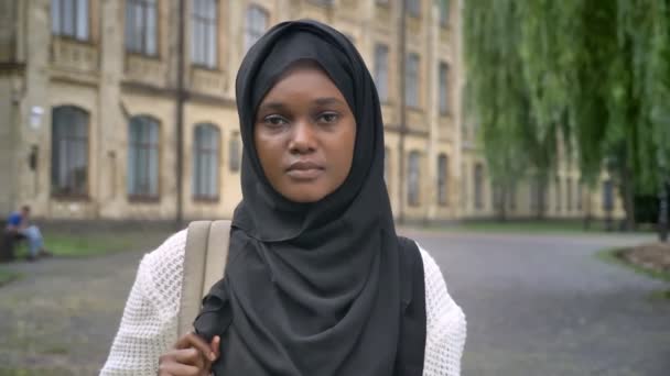 Młoda kobieta smutny Afryki muzułmańskich w hidżab patrząc na kamery i stojąc w parku, w pobliżu Uniwersytetu i wyrażenie zestresowany — Wideo stockowe