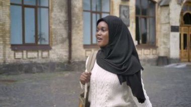 Üniversite ve birine, mutlu ve neşeli sallayarak Parkı yürüme hijab genç Afro-Amerikan Müslüman kadın