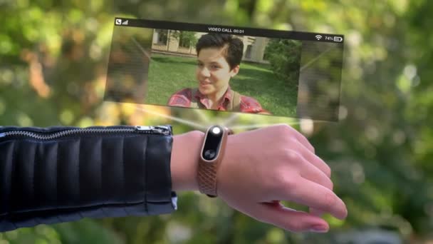Meisje sportman hand Bel vriend die wordt weergegeven in een hologram. Smart watch futuristisch en technologische. Groene bomen in de achtergrond. — Stockvideo
