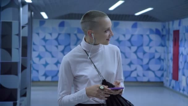 Félelmetes mosolygó kopasz kaukázusi lány metró, városi mozgás, kék háttérrel, álmodik — Stock videók