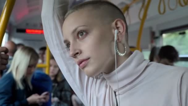 Cincere λυπημένο βλέμμα του φαλακρός καυκάσιος γυναίκα να στέκεται στο δημόσιο λεωφορείο κοντά σε παράθυρο, ήρεμη και σκέψης ενώ ακούτε μουσική — Αρχείο Βίντεο