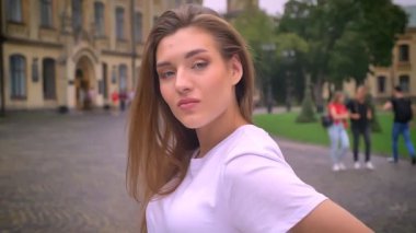 sevimli beyaz kız kamera ve seyir düz hareket, şehir manzaralı, sokak, gündüz, soğuk gülümsüyor