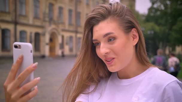 Érzelmi félelmetes kaukázusi nő van birtoklás video hív, az utcán, nevetve, és beszél neki a smartphone, nappali — Stock videók