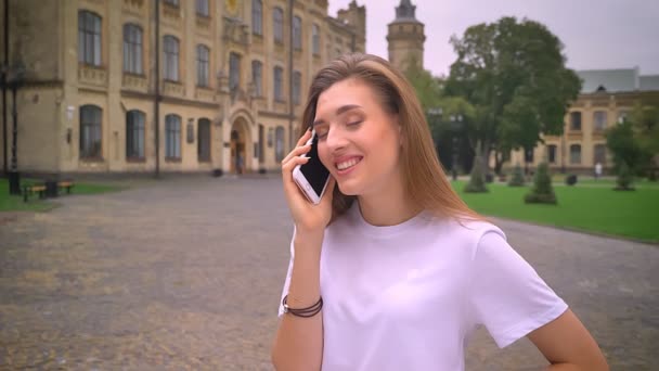 Klid a světlo telefonní konverzace roztomilý kavkazský dívky, stojící přímo na staré krásné ulici, denní — Stock video