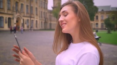 güzel beyaz kadın mavi ekran onun tablet üzerinde işaret ve mutlu bir şekilde arkasında, gündüz sokak ve eski binaları ile gülümseyen