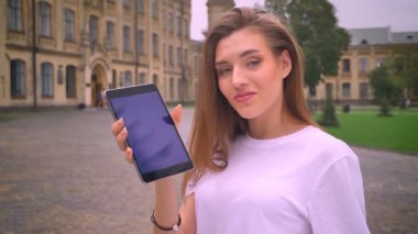 güzel beyaz kız onun tablet swiping ve sonra kamera ile güven, şehir manzaralı düz, mavi ekran gösterilen