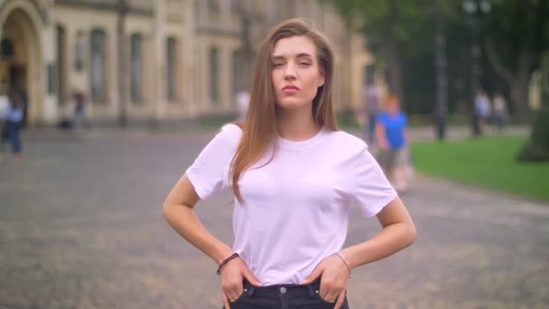 Awesome Kaukasische vrouw staat met haar handen op de heupen en zeker kijken camera, stad achtergrond, overdag — Stockvideo