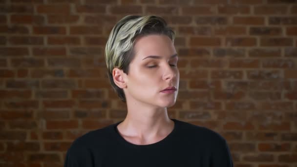 Ruhige und selbstbewusste Frau dreht den Kopf und blickt direkt in die Kamera mit entspanntem Gesicht und natürlicher Pose im roten Studio — Stockvideo