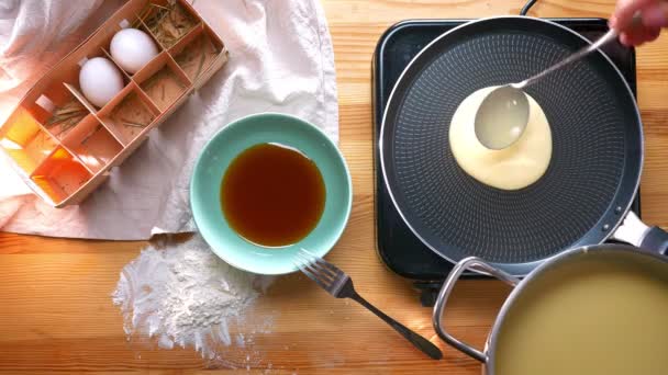 Top shot, appetizing pancake is being cooked with frying pan on wooden table, healthy food preparation at home — Stock Video