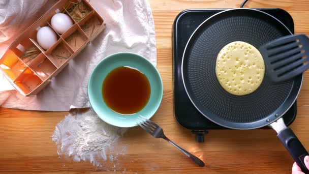 Top shot, tasty pancake is fried from both sides on pan with eggs and honey additionally, flour product cooking — Stock Video