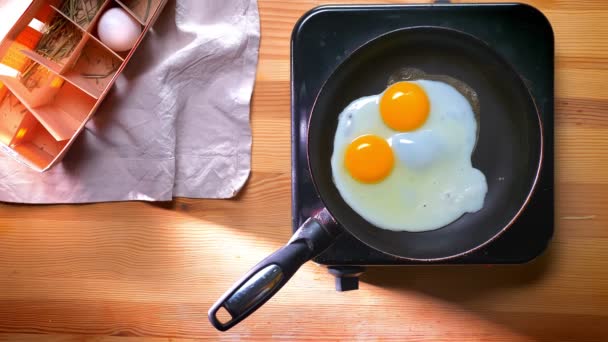 Κορυφή πλάνο, προσθέτοντας αλάτι σε σχεδόν βρασμένα αυγά στο τηγάνι στο σπίτι, υγιείς διατροφικές συνήθειες εσωτερική, απλό φαγητό — Αρχείο Βίντεο