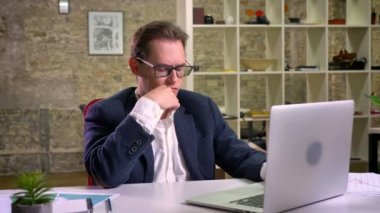 Laptop beyaz bilgisayar kapalı, yakın çalışma evinde oturan beyaz iş adamı düşünme