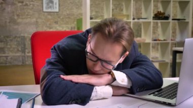 Sakin beyaz işadamı yalnız işyerinde uyuyan ve bir süre sonra bilgisayar çalışmaya devam