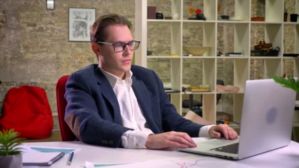 Upset caucasian man stopped his work at the table on laptop thinking and looking straight, indoor, office vibes — Stock Video