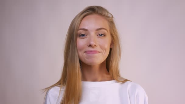 Calma hermosa sonrisa de rubia caucásica chica de pie aislado en luz estudio felizmente — Vídeo de stock