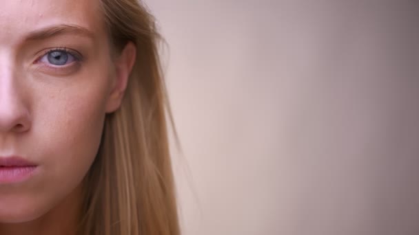 Полупортрет красивой белокурой белокурой девушки, стоящей в одиночестве в светлой студии — стоковое видео