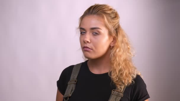 Koncentrerad utseendet på trevliga kaukasiska lockigt kvinna, står bredvid den grå bakgrunden i studion — Stockvideo