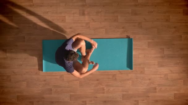 Top shot, caucasian man is meditating on a blue yoga mat relaxed and enjoying process deeply and focused on wooden floor — Stock Video