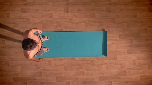 トップ ショット、フィットの上半身裸の男性は、光 stutio の青いマット、osphere でリラックス、木の床の様々 な joga の位置を練習します。 — ストック動画