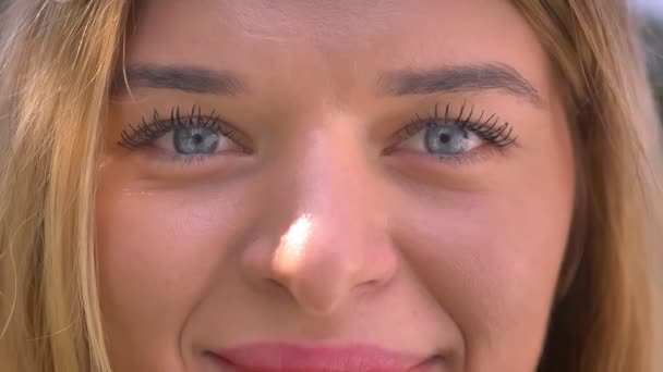 Close-up grote blauwe ogen van Kaukasische vrouw die op zoek is naar recht en lachende buiten — Stockvideo