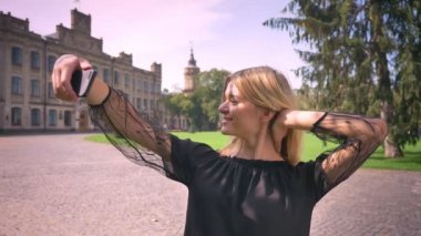 Mutlu beyaz kadın selfies ise düz sokakta duran ve gülümseyen, eski binalar zemin üzerine alarak