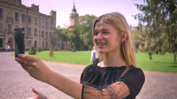 Impressionnant femme caucasienne fait signe à sa caméra de téléphone et avoir une conversation sur le web tout en se tenant dans la rue en ville et souriant — Video