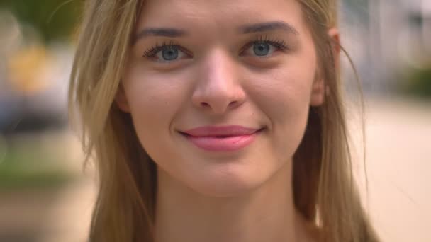 Close-up retrato de menina branca bonita com grandes olhos azuis rindo sinceramente ao ar livre — Vídeo de Stock