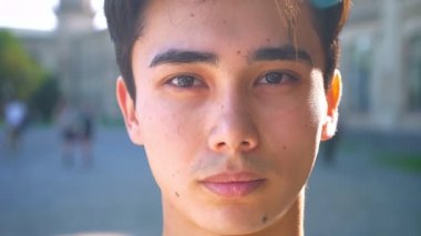 Asyalı erkek kameraya düz, ciddi seyir yakın çekim portre gölge havamda konsantre, açık yaz