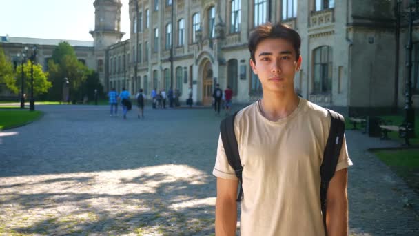 Lindo asiático chico es sonriendo en cámara al aire libre, mientras de pie derecho cerca hermoso antiguo edificio — Vídeos de Stock