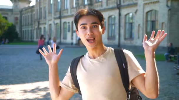 Awesome surprised asian guy is showing confused gesture with emotional face while standing next to the old building alone — Stock Video