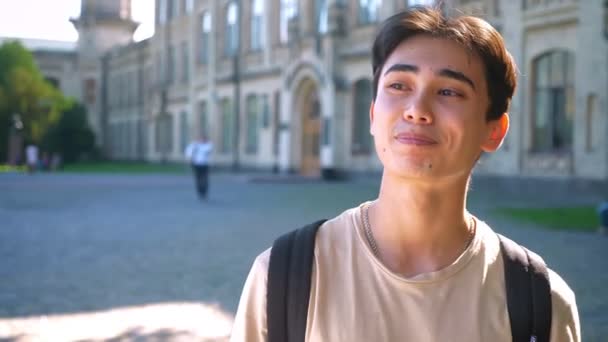 Glad asiatiska pojke man leenden i hängslen stående mitt i tomma gatan, stadsområde, sunlights — Stockvideo