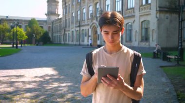 Korku veren Asyalı adam onun tablet sakince swiping ve güneşli havalarda ve rahat hava dışında yalnız sokakta duran