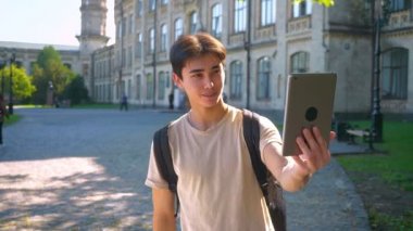 Memnun Asya erkek selfies alarak onun tablet ve düz ayrılmış okul binası yakınında duran, yaz