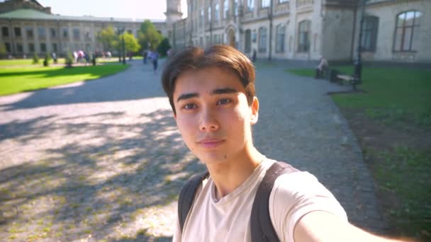 Feliz seguro asiático chico es celebración selfie cámara y tomando vídeo en la luz del sol cerca de hermosa viejo edificio, escalofriante — Vídeo de stock