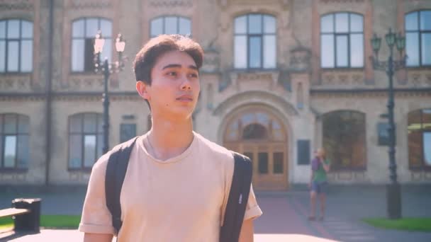 Frisches Shooting des süßen asiatischen Jungen, der auf die Kamera zugeht und sich nach vorne freut, während es sonnige perfekte Heide und gemütliche Stadtansichten sind — Stockvideo