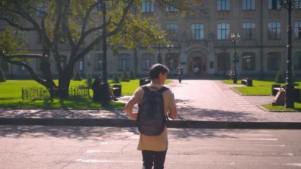 Обратная съемка прохладный азиатский мужчина, пересечение дороги на пешеходном переходе, направление в колледж — стоковое видео