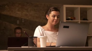 İki sevimli beyaz çalışma dizüstü yanında oturan kız, yazarak, bir odaklı kadın kahve tuğla ofiste içiyor