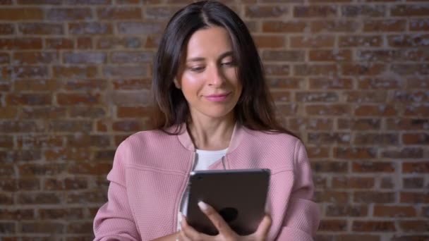 Yeşil ekran tablet kamera düz, gösterilen gurur emin görünümü ile keyifli beyaz esmer kız izole brick kırmızı studio — Stok video